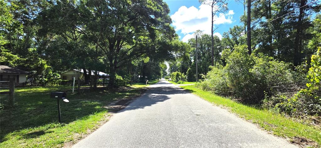 A paved road runs through a wooded residential area with houses and mailboxes on the side — TBD Lot 11 NW 61ST LANE, OCALA, FL