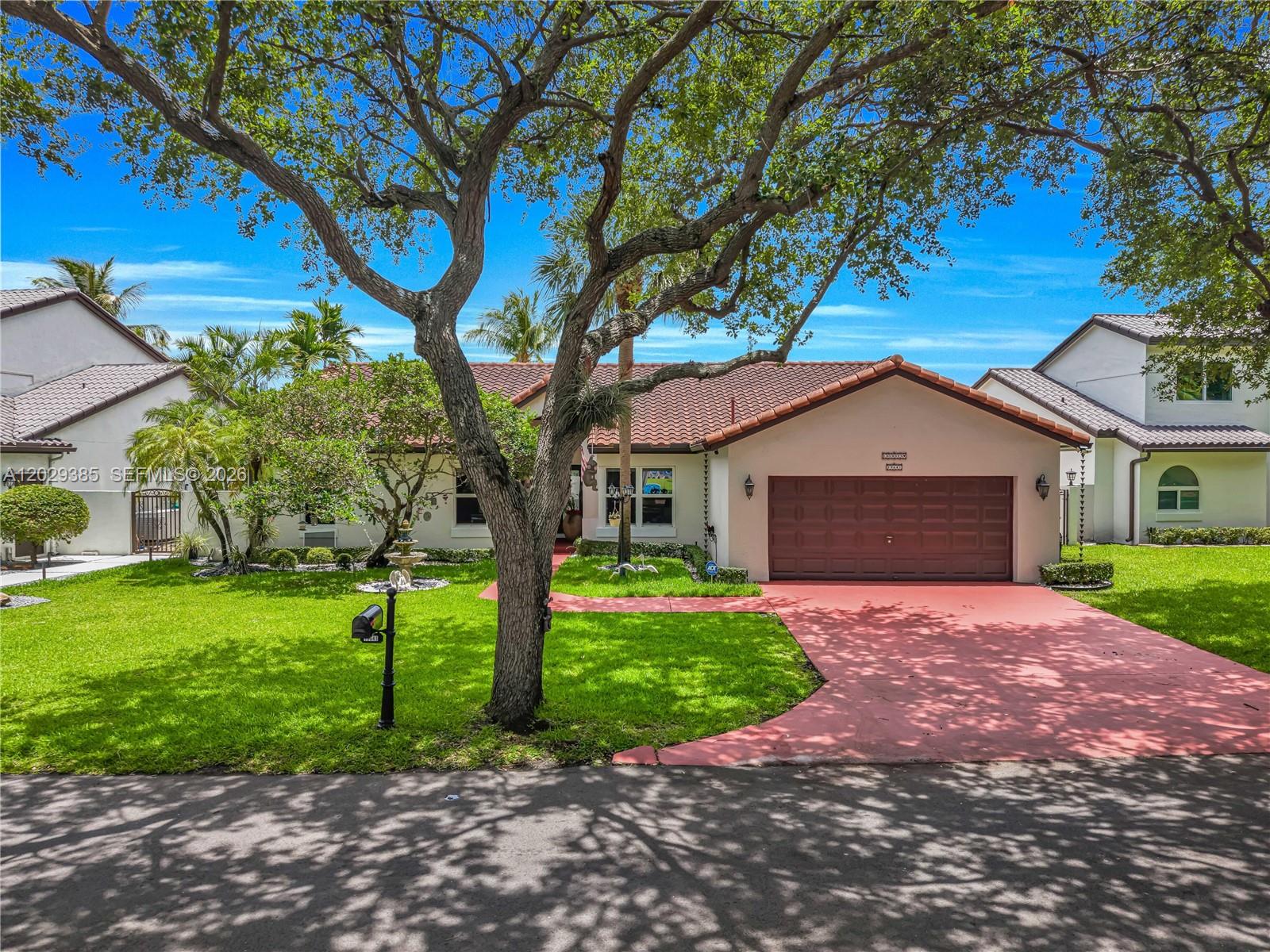 A single-story house with a red-painted driveway, a brown garage door, and a large tree — 19641 NW 88th Ave, Hialeah FL 33018, HIALEAH, FL