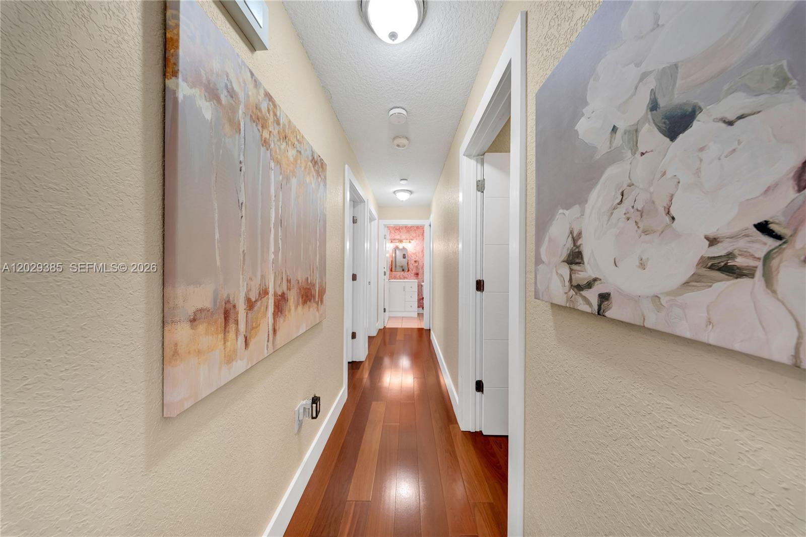 A hallway with wood flooring, two large wall paintings, and recessed ceiling lighting — 19641 NW 88th Ave, Hialeah FL 33018, HIALEAH, FL