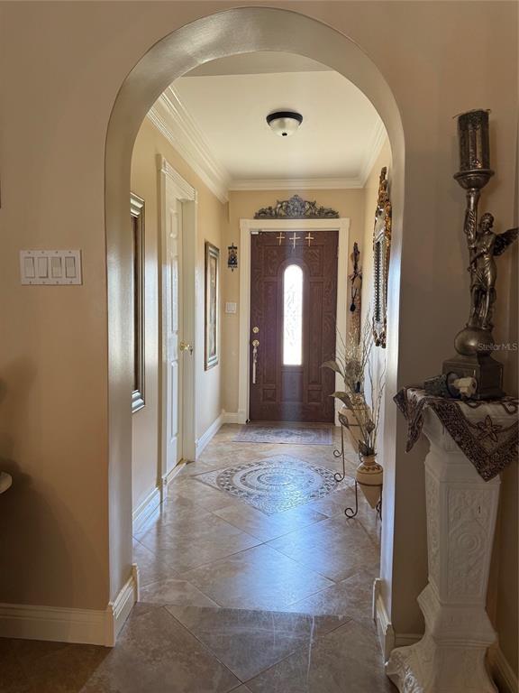 An arched entryway leads to a front door with a decorative tile floor inlay — 9201 BARRINGTON LANE, PORT RICHEY, FL