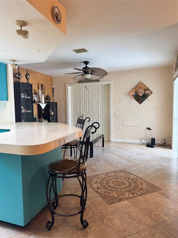 A kitchen with a turquoise island, bar stools, and a textured wall in an open room — 9201 BARRINGTON LANE, PORT RICHEY, FL
