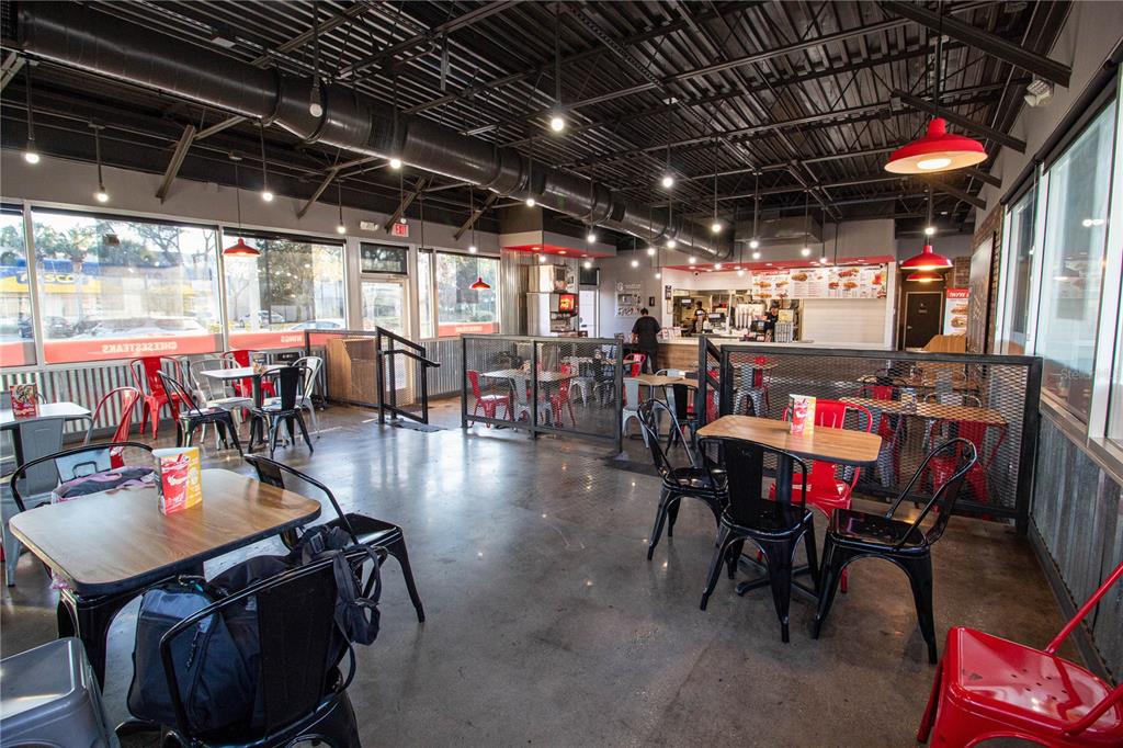 An industrial-style restaurant interior features concrete floors, exposed ceiling ducts, and red metal chairs — 5908 S ORANGE BLOSSOM TRAIL, ORLANDO, FL