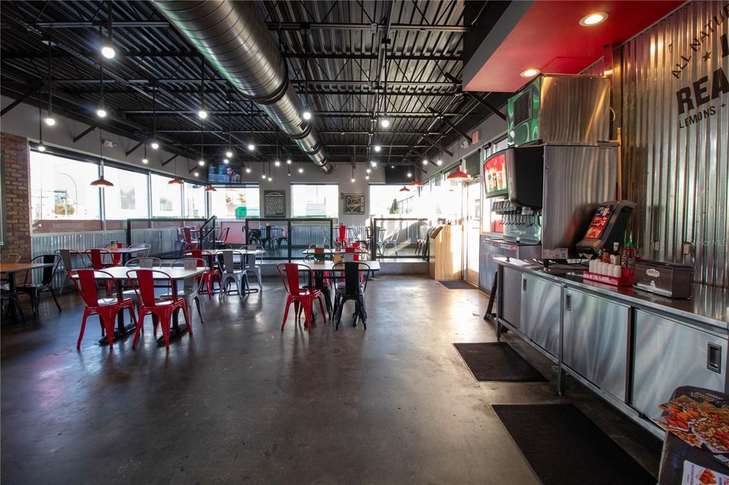 An industrial-style restaurant dining area features metal tables, red chairs, and exposed ceiling ductwork — 5908 S ORANGE BLOSSOM TRAIL, ORLANDO, FL
