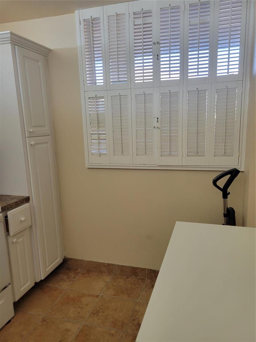 A laundry room features white cabinetry, tile flooring, and plantation shutters over a window — 3671 Environ Boulevard # 468, Lauderhill FL 33319, LAUDERHILL, FL