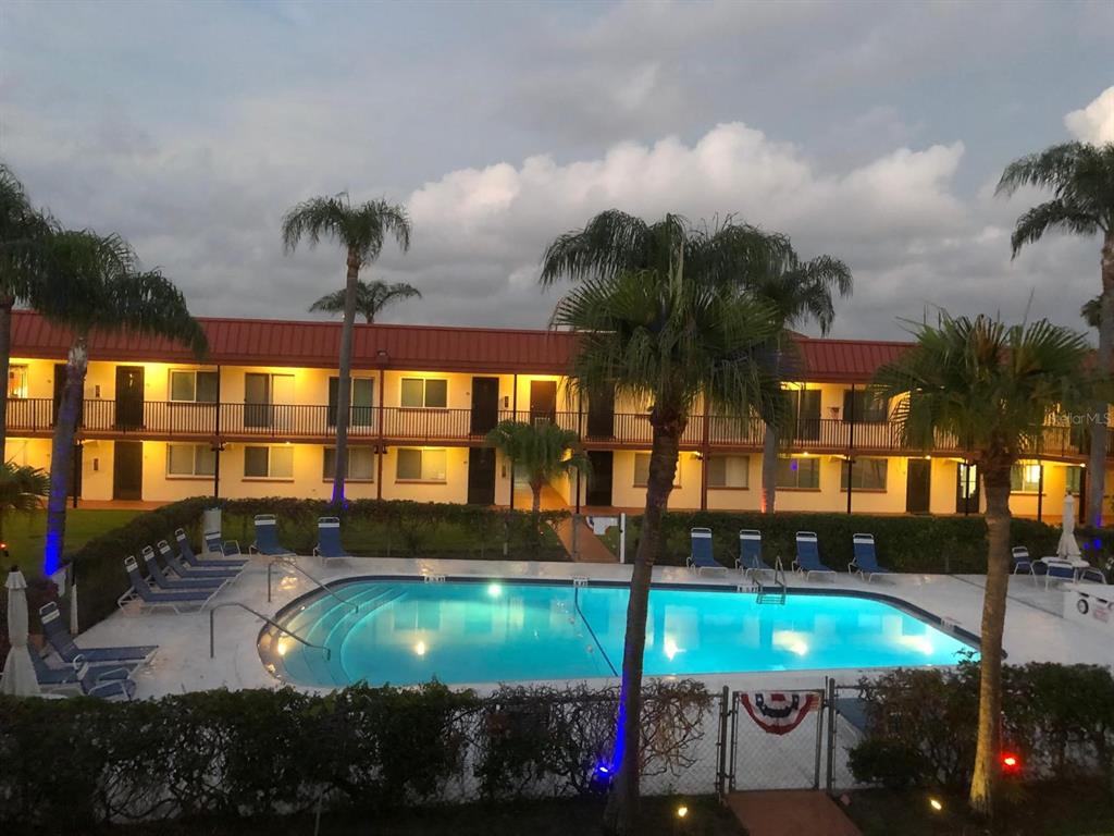 A two-story motel building with a swimming pool and palm trees in the foreground — 10365 PARADISE BOULEVARD UNIT 16, TREASURE ISLAND, FL