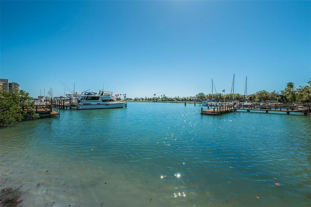 A view of a marina with several boats docked at wooden piers under a clear sky — 10365 PARADISE BOULEVARD UNIT 16, TREASURE ISLAND, FL