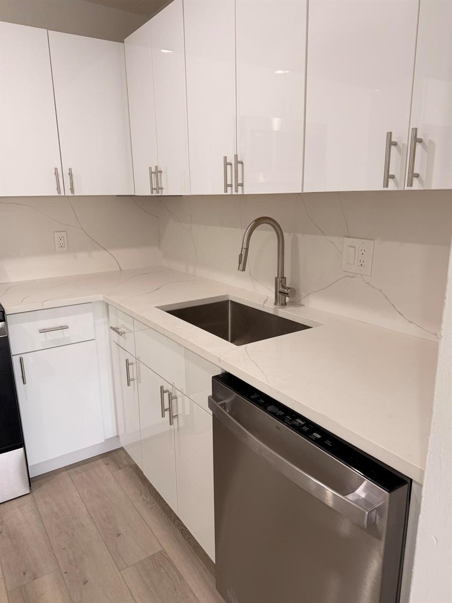 A modern kitchen features white glossy cabinets, quartz countertops, and stainless steel appliances — 10401 SW 108th Avenue # 240, Miami FL 33176, MIAMI, FL
