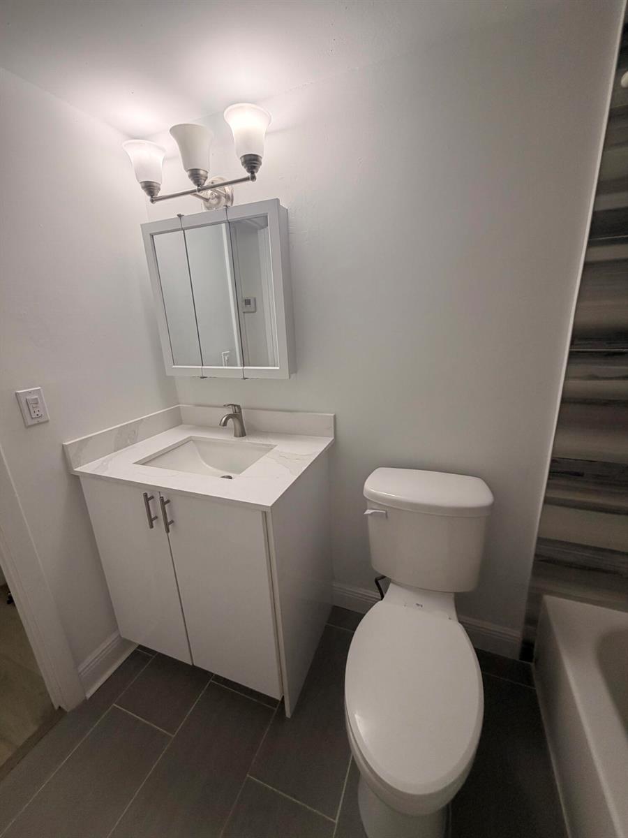 A bathroom features a white vanity with a stone countertop, a medicine cabinet, and toilet — 10401 SW 108th Avenue # 240, Miami FL 33176, MIAMI, FL