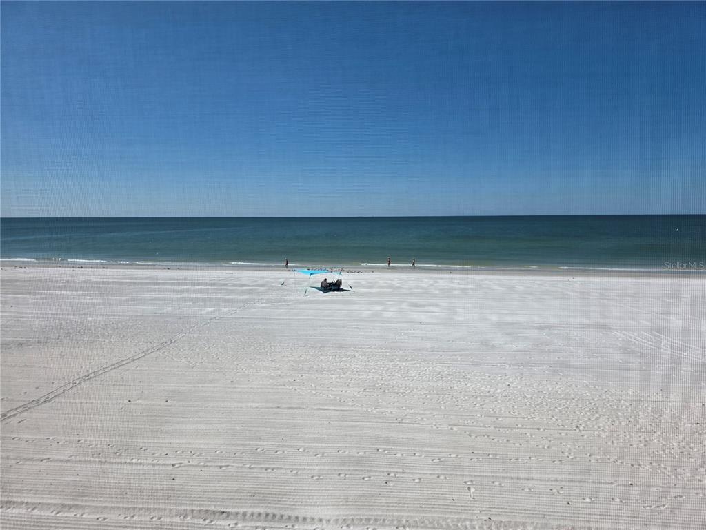 A view of a white sand beach and the ocean from behind a screen — 17580 GULF BOULEVARD UNIT 311, REDINGTON SHORES, FL