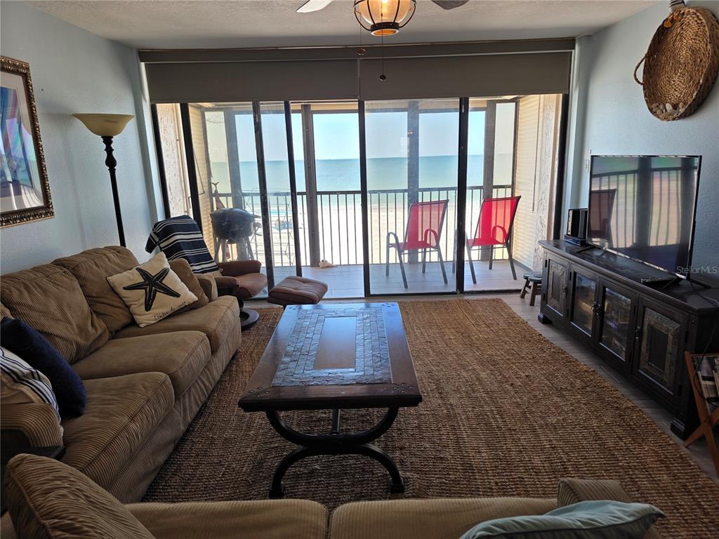 A living room features a brown sofa, coffee table, and sliding glass doors overlooking the beach — 17580 GULF BOULEVARD UNIT 311, REDINGTON SHORES, FL