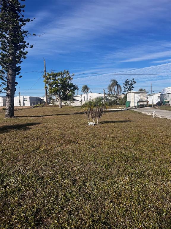 A large, grassy vacant lot features a few small palm trees and a distant shed — 1348 FLAMINGO DRIVE, ENGLEWOOD, FL