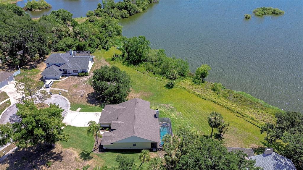 An aerial view shows two houses with swimming pools situated near a large lake — 709 SPORTSMAN PARK DRIVE, SEFFNER, FL