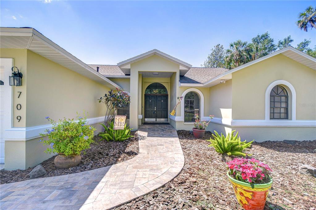 The exterior of a single-story house features a stone walkway leading to a dark entryway — 709 SPORTSMAN PARK DRIVE, SEFFNER, FL