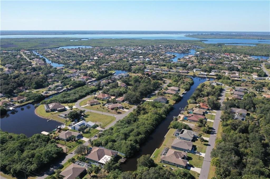 An aerial view shows houses situated along canals near a large body of water — 17404 PHEASANT CIRCLE, PORT CHARLOTTE, FL
