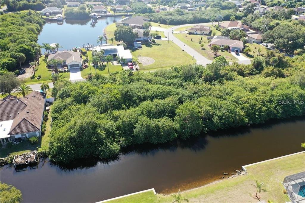 An aerial view shows a canal, dense trees, and several residential houses with driveways — 17404 PHEASANT CIRCLE, PORT CHARLOTTE, FL