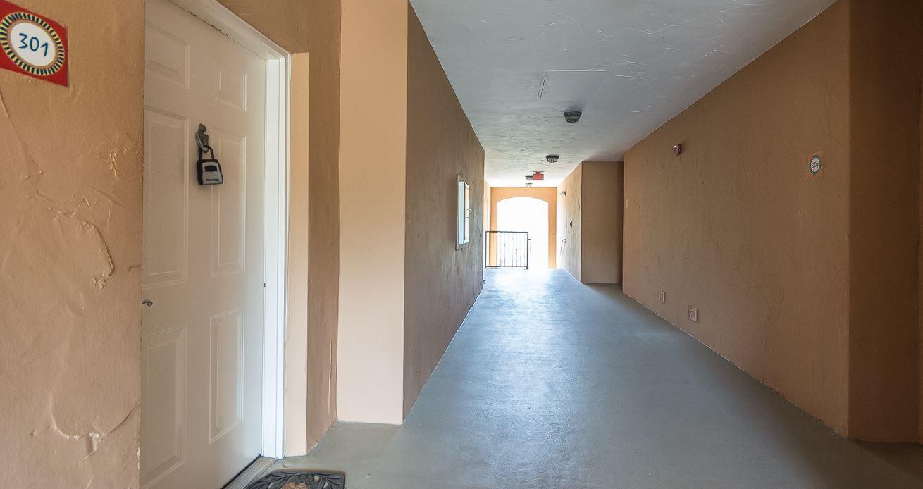 A beige apartment hallway features a white door labeled 301 and a concrete floor — 5080 Fairways Circle # G301, Vero Beach FL 32967, VERO BEACH, FL