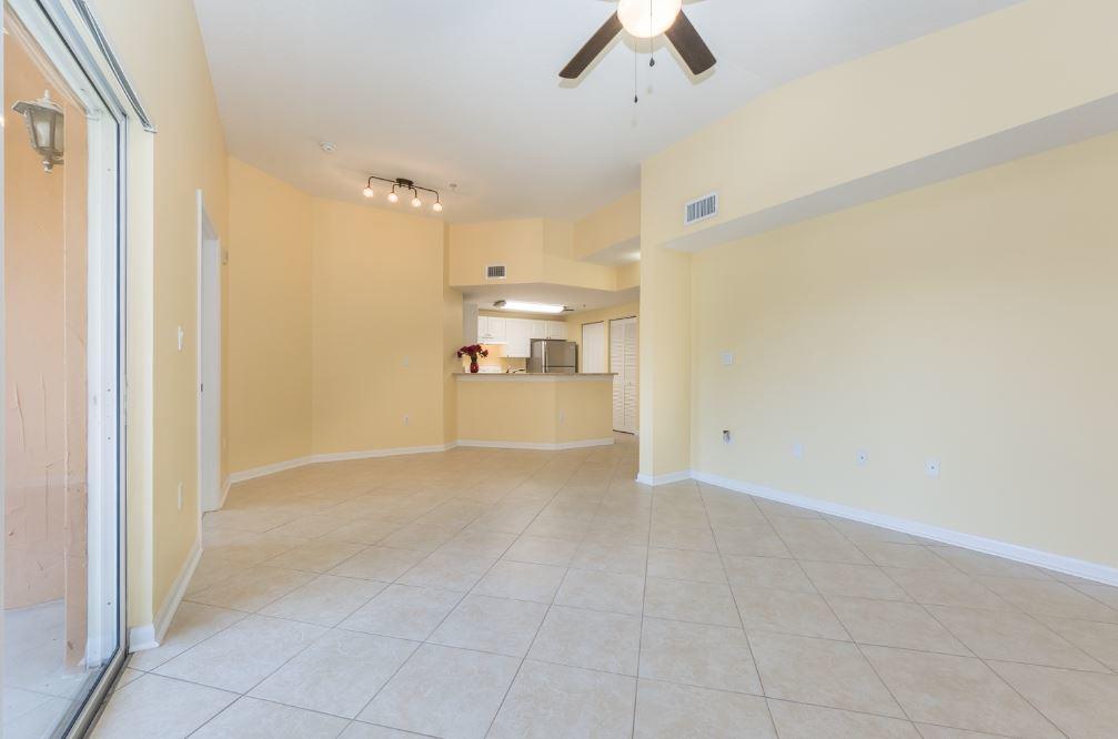 An open-concept living area features light yellow walls, beige tile flooring, and a kitchen pass-through — 5080 Fairways Circle # G301, Vero Beach FL 32967, VERO BEACH, FL