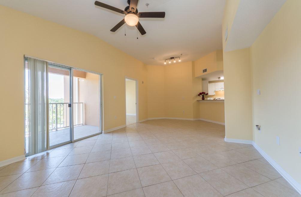An open-concept living area with yellow walls, tile flooring, a ceiling fan, and a balcony — 5080 Fairways Circle # G301, Vero Beach FL 32967, VERO BEACH, FL