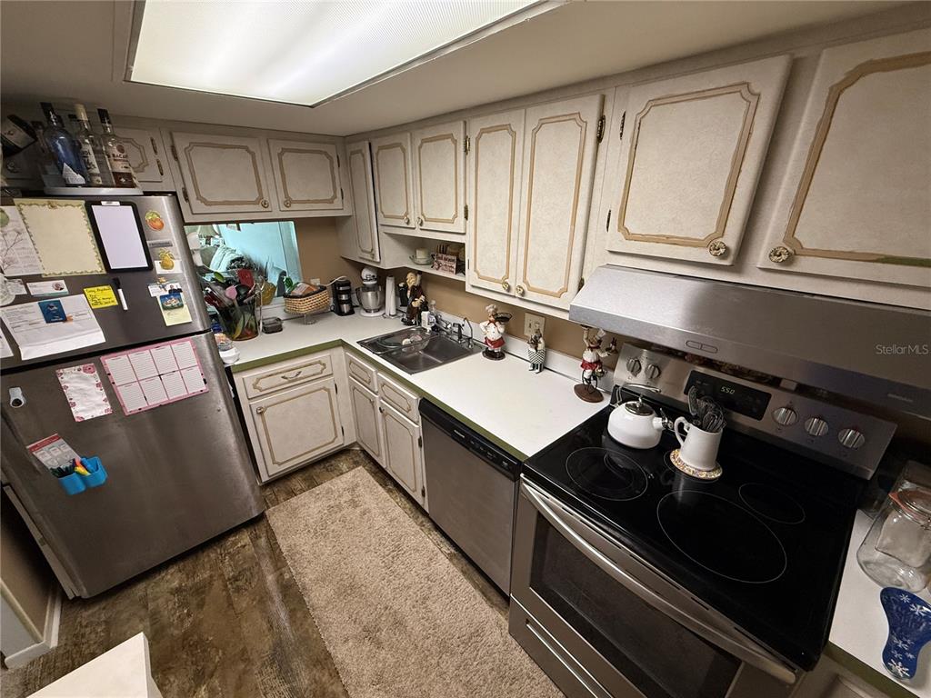 A kitchen features stainless steel appliances, white cabinets with gold trim, and a laminate countertop — 700 MIRROR TERRACE NW UNIT 303, WINTER HAVEN, FL