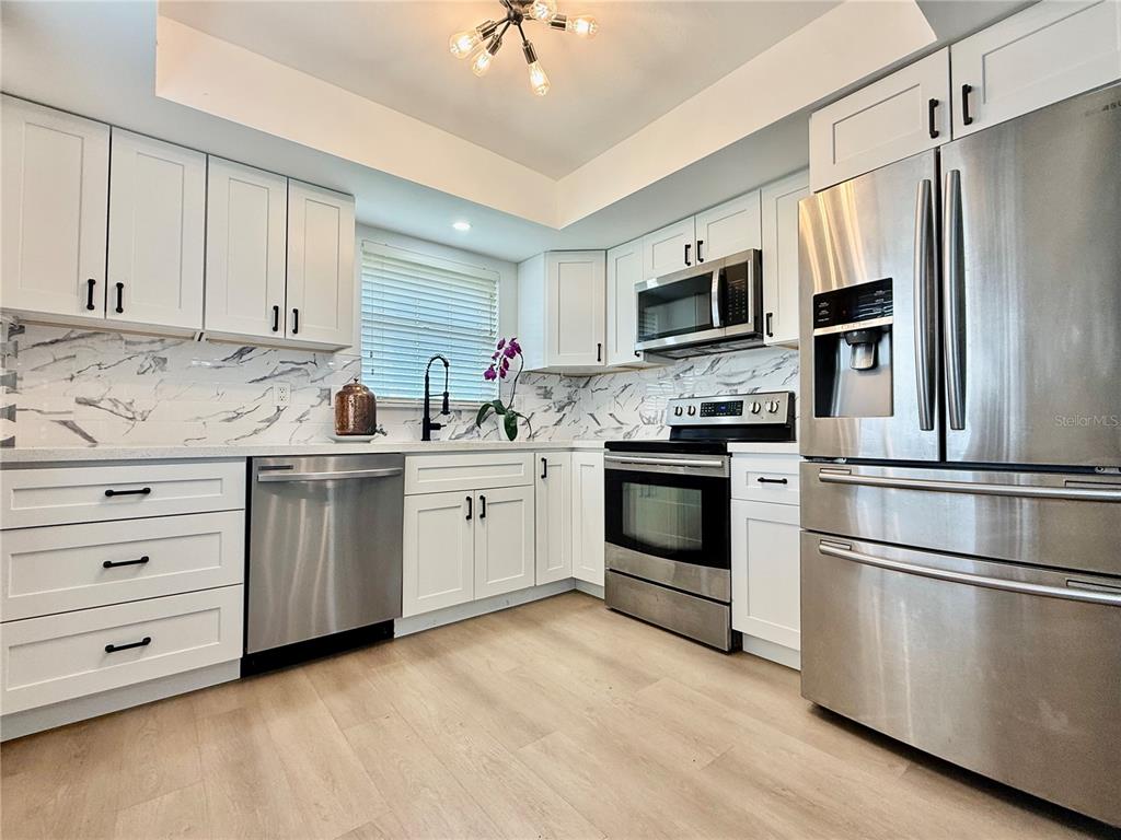 A kitchen with white cabinets, stainless steel appliances, and a marble-patterned backsplash — 5440 RIVERBLUFF CIRCLE UNIT 87, SARASOTA, FL