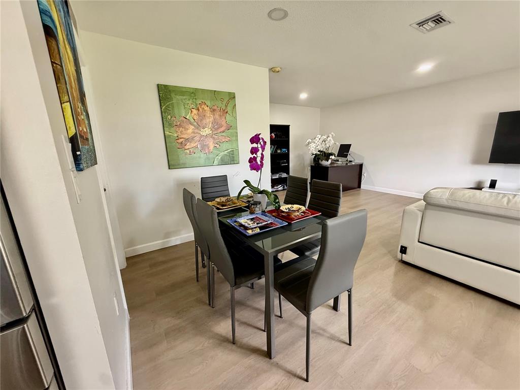 A dining area with a glass table and grey chairs sits next to a living room — 5440 RIVERBLUFF CIRCLE UNIT 87, SARASOTA, FL