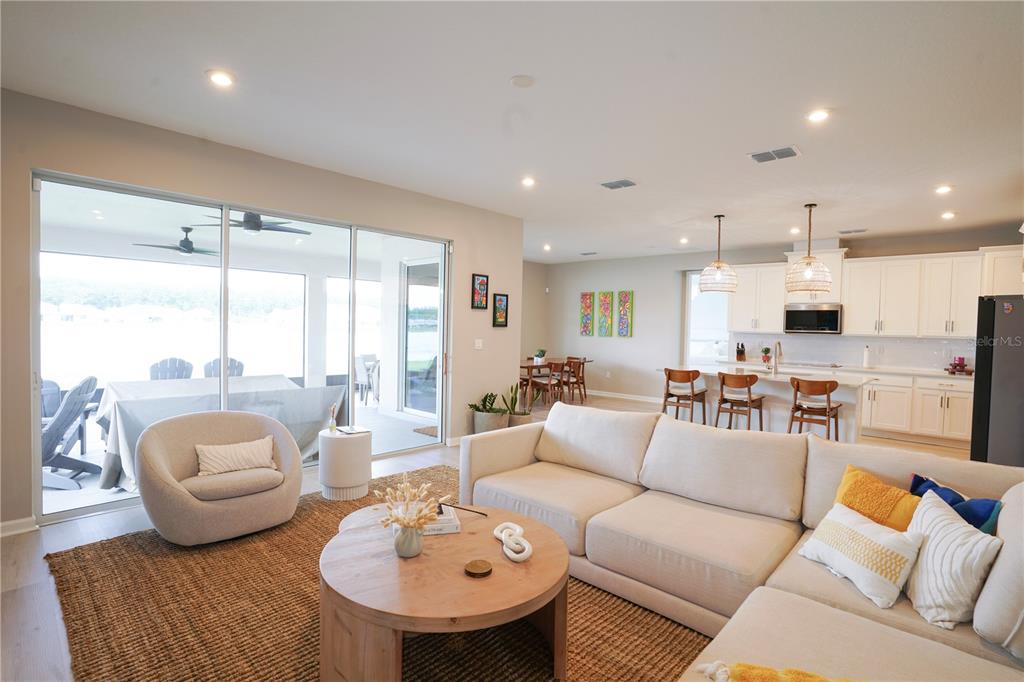 A bright open-concept living room and kitchen featuring a sectional sofa, round table, and patio — 7964 WATERFIELD AVENUE, ORLANDO, FL