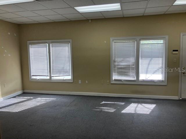 An empty office room with beige walls, gray carpeting, and two windows with white blinds — 5001 S MACDILL AVENUE UNIT 100, TAMPA, FL