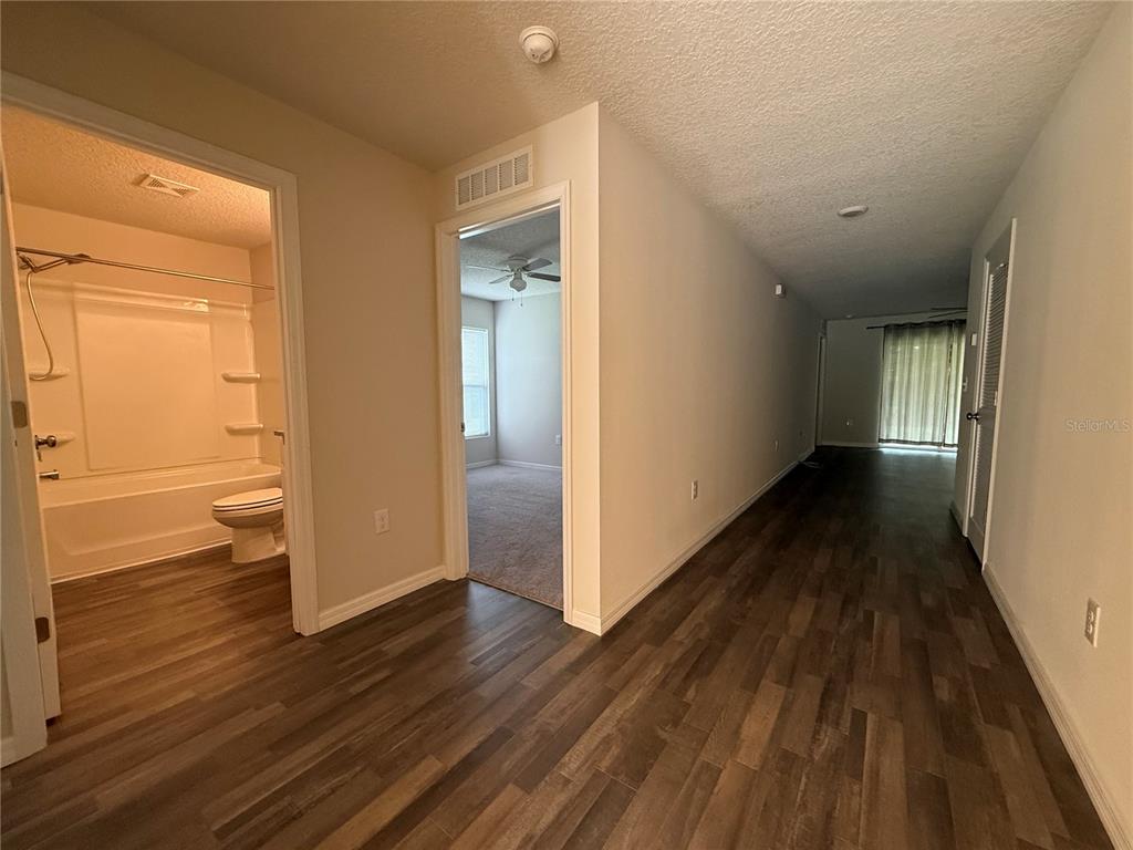 A hallway with wood-look flooring leads to a bathroom, a bedroom, and a living area — 1399 W CARY DRIVE, CITRUS SPRINGS, FL