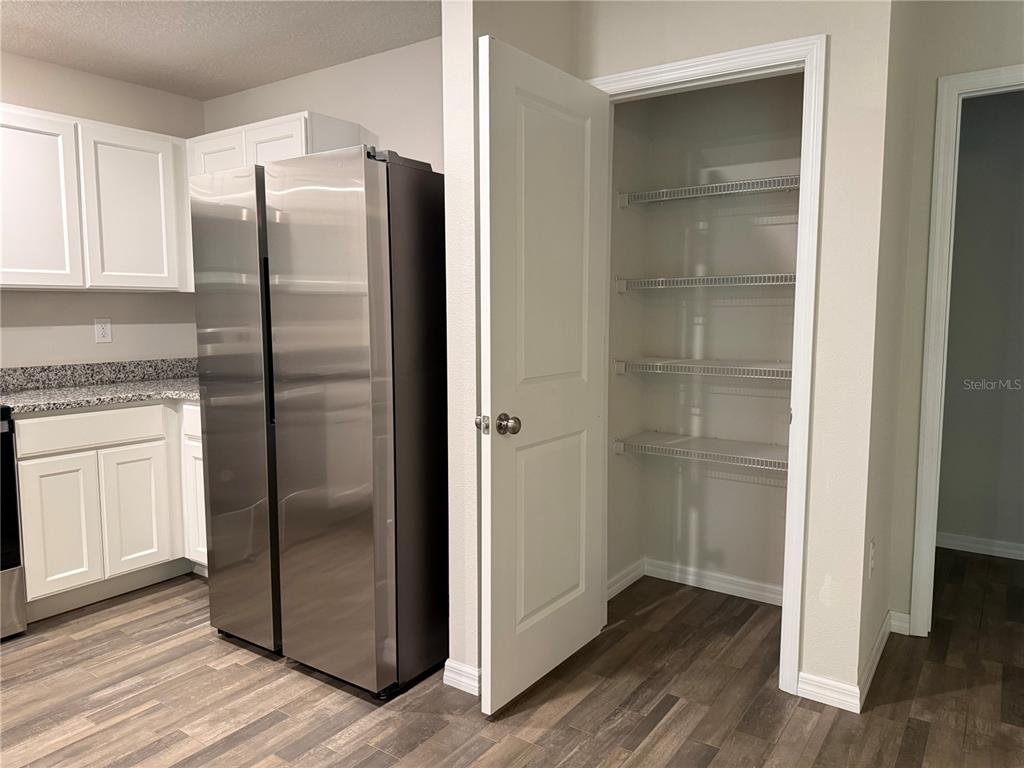 A kitchen features white cabinets, stainless steel appliances, and an open pantry with wire shelving — 1399 W CARY DRIVE, CITRUS SPRINGS, FL