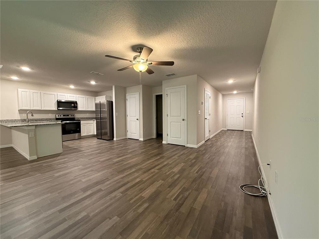 An open-concept kitchen and living area feature wood-look flooring, white cabinetry, and stainless appliances — 1399 W CARY DRIVE, CITRUS SPRINGS, FL