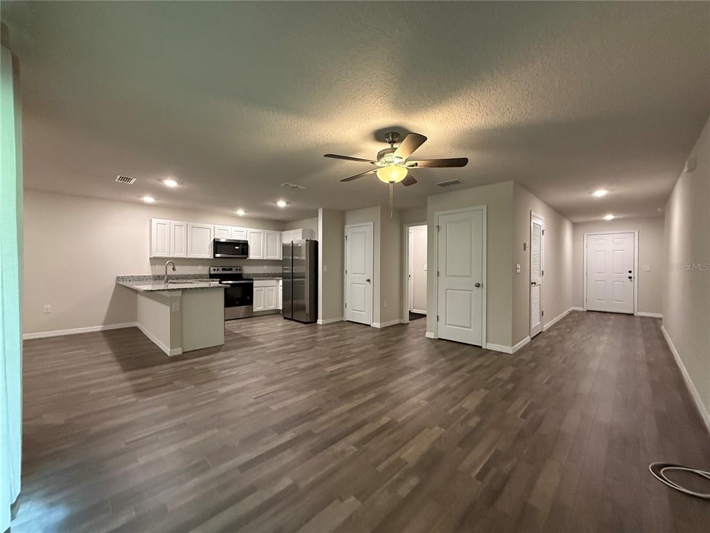 An open-concept kitchen and living area features wood-look flooring, white cabinetry, and a ceiling fan — 1399 W CARY DRIVE, CITRUS SPRINGS, FL