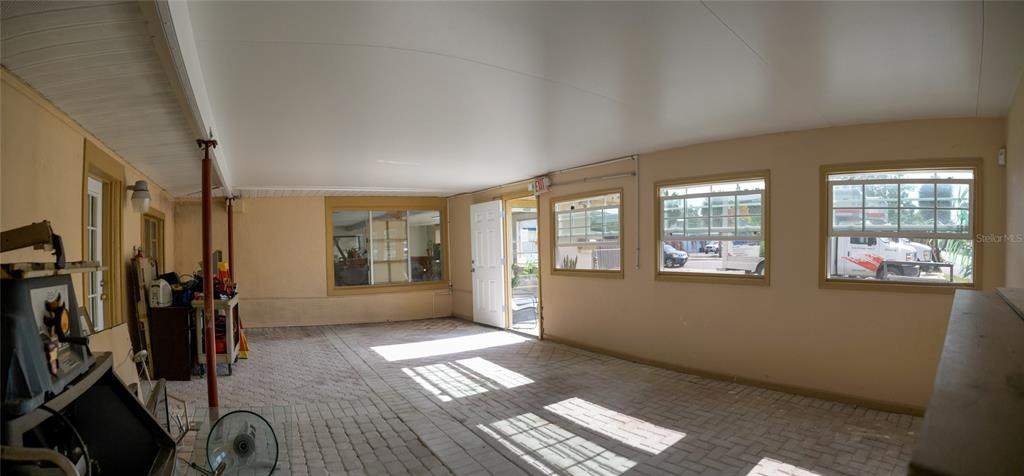 A covered patio with a brick floor, multiple windows, and a white door — 1220 CLEARWATER LARGO ROAD N, LARGO, FL