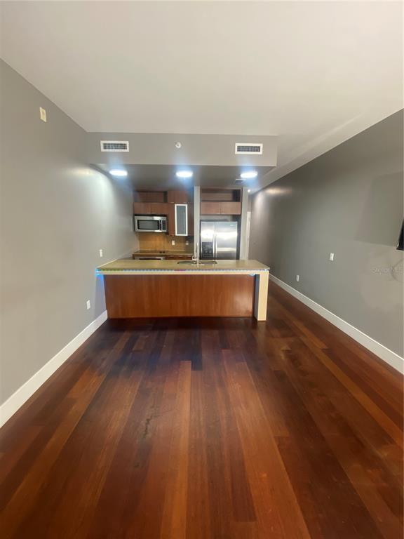 A kitchen with wood cabinets and a breakfast bar overlooks a room with hardwood floors — 111 N 12TH STREET UNIT 1411, TAMPA, FL