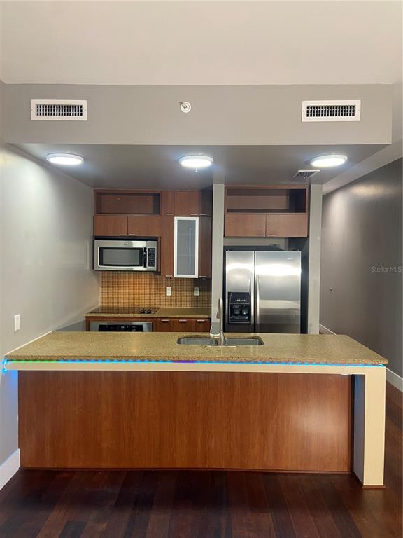 A kitchen features wood cabinets, stainless steel appliances, and a granite-topped island with LED lighting — 111 N 12TH STREET UNIT 1411, TAMPA, FL
