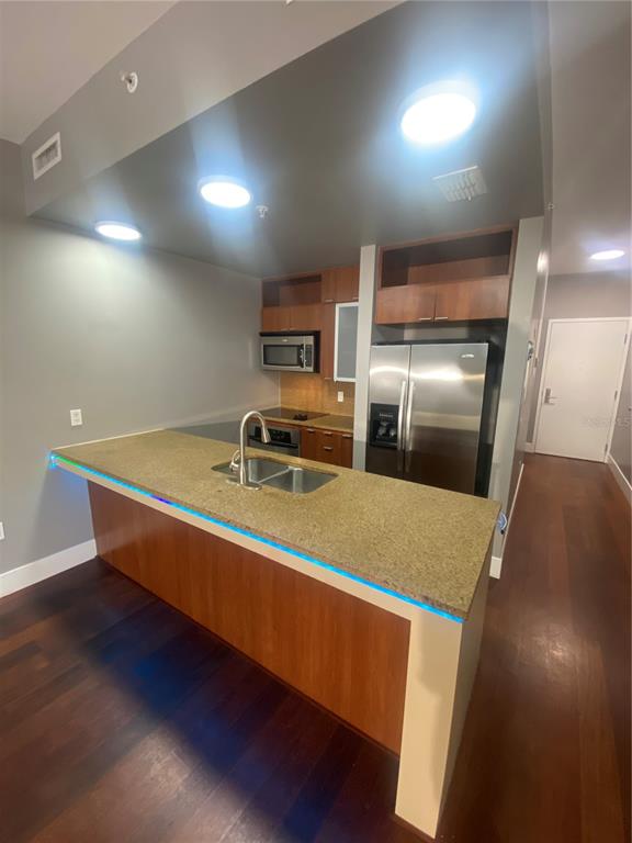 A kitchen with wood cabinets, stainless steel appliances, and a granite island with blue lighting — 111 N 12TH STREET UNIT 1411, TAMPA, FL