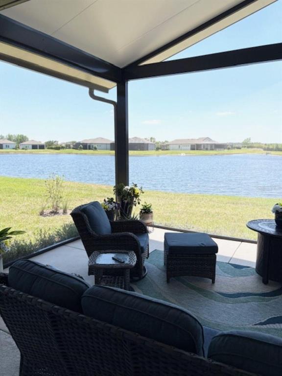 A screened-in patio with wicker furniture overlooks a lake and neighboring houses — 18498 COASTAL SHORE TERRACE, LAND O LAKES, FL
