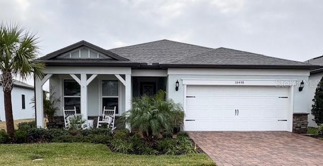 A single-story house with a white garage, a covered front porch, and a paved driveway — 18498 COASTAL SHORE TERRACE, LAND O LAKES, FL