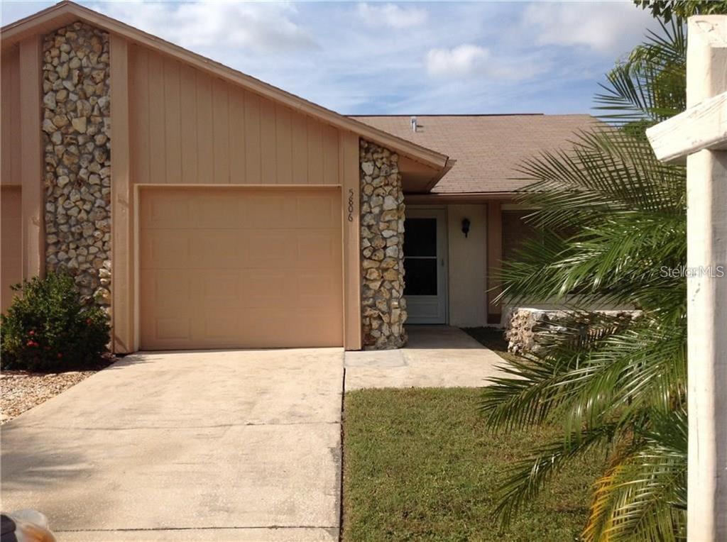 A single-story house features a tan exterior, a stone facade, and an attached garage — 5806 MARBLE COURT, WINTER PARK, FL
