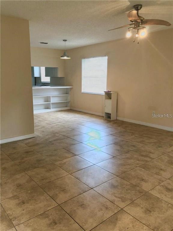 An open living area features tan tile flooring, a ceiling fan, and a kitchen pass-through — 5806 MARBLE COURT, WINTER PARK, FL