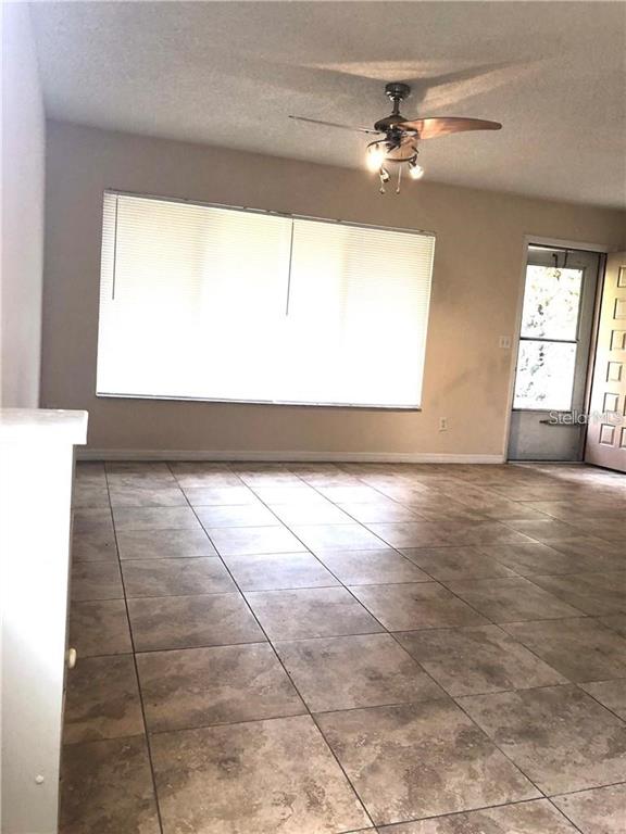 A living room features large windows with blinds, a ceiling fan, and tiled flooring — 5806 MARBLE COURT, WINTER PARK, FL