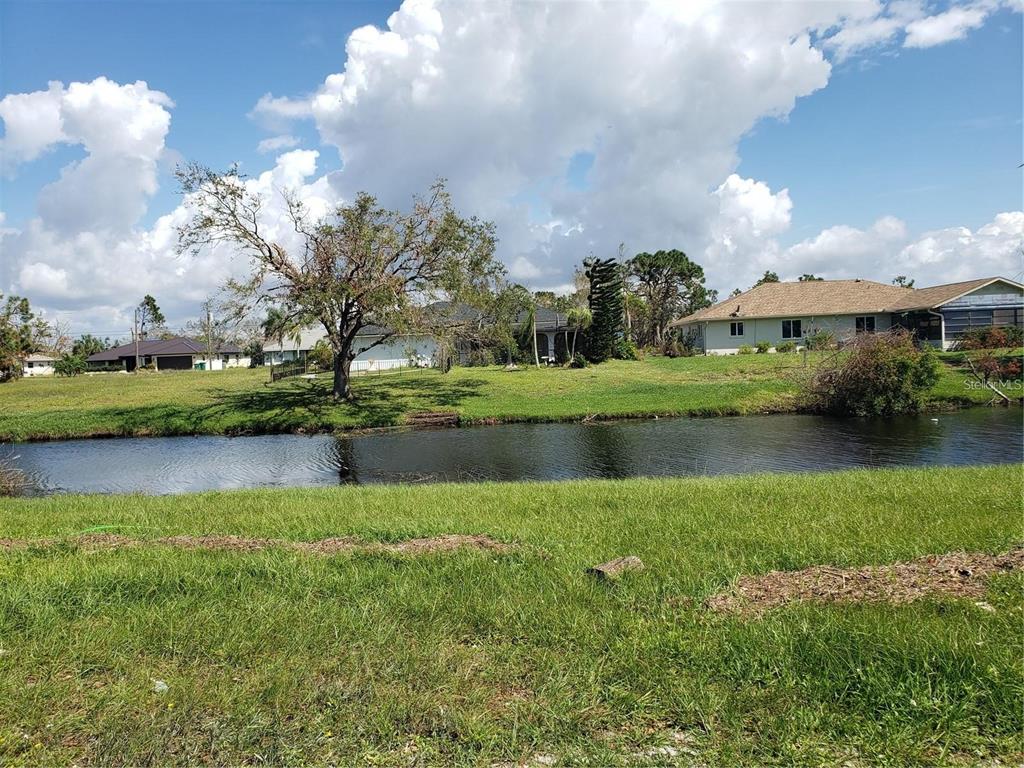A grassy yard overlooks a small pond with houses visible in the background — 191 BUNKER ROAD, ROTONDA WEST, FL