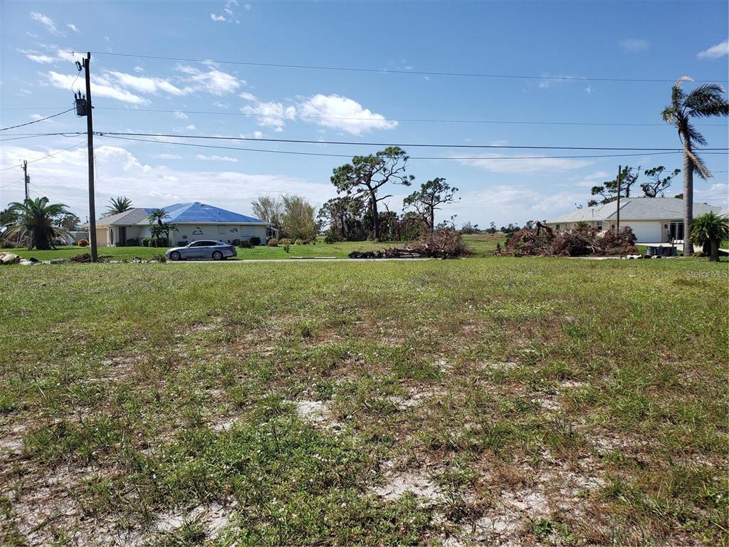 A vacant, grassy lot with scattered debris and neighboring houses in the background — 191 BUNKER ROAD, ROTONDA WEST, FL