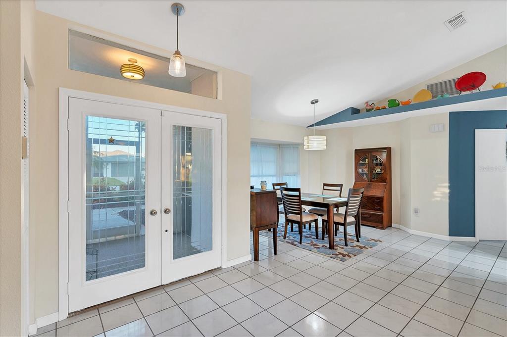 A dining area with tile floors, a wooden table, and a blue decorative wall ledge — 25 FAIRWAY ROAD, ROTONDA WEST, FL