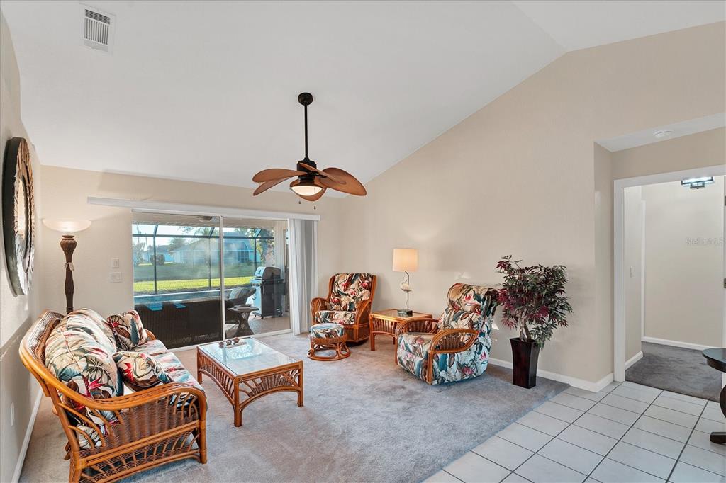 A living room features wicker furniture, a ceiling fan, and a sliding glass door — 25 FAIRWAY ROAD, ROTONDA WEST, FL