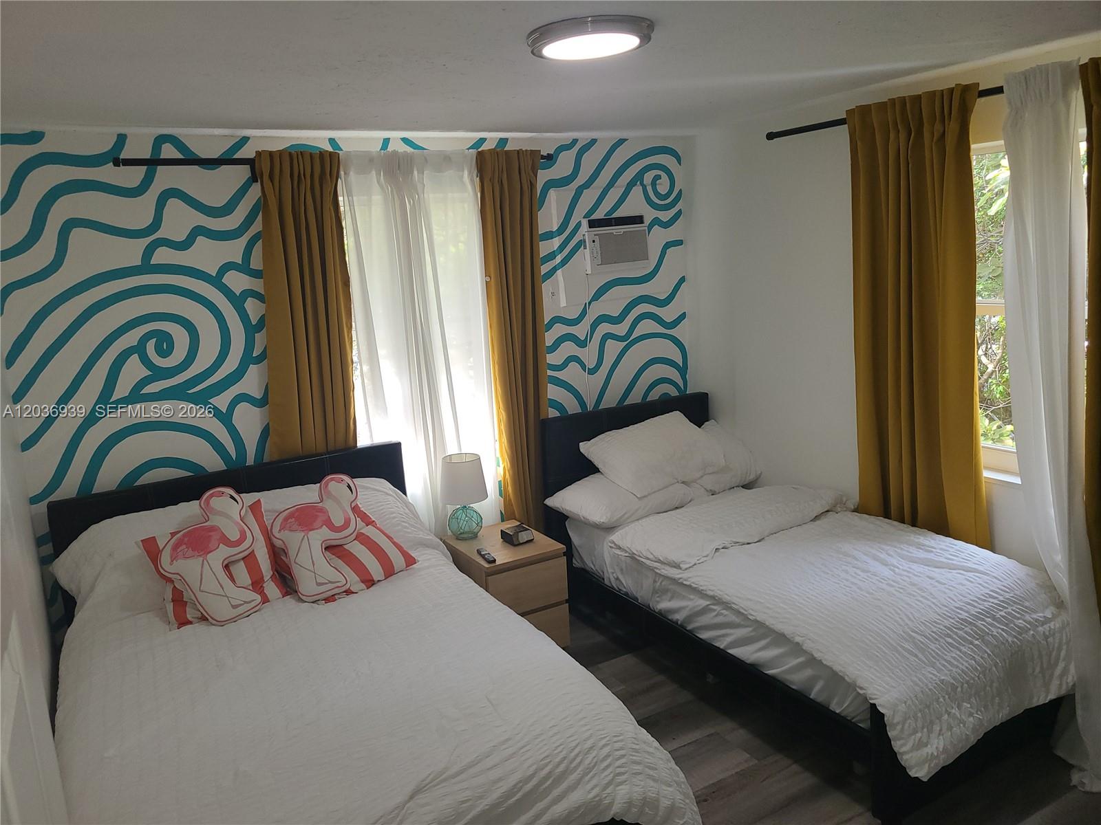 A bedroom features two beds, mustard curtains, and a wall with blue wave-patterned wallpaper — 168 NW 32nd St # 6, Miami FL 33127, MIAMI, FL