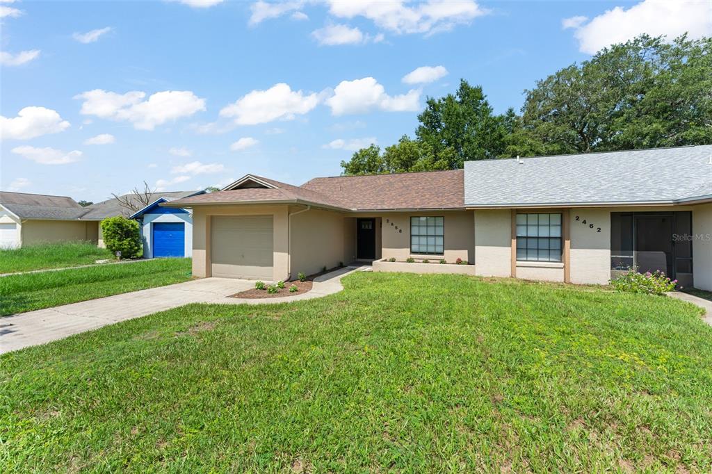 A single-story house with a tan exterior, a garage, and a front lawn — 2458 LONG MEADOW WAY, ORLANDO, FL