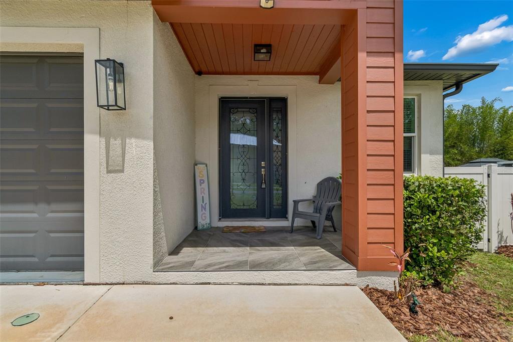 A front porch with a gray front door, a chair, and a decorative spring sign — 1901 W CLUSTER AVENUE, TAMPA, FL