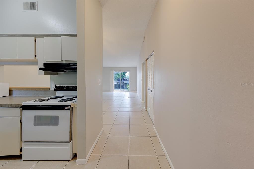 A kitchen with white appliances and cabinets opens into a tiled living area with sliding doors — 1109 E ROHE STREET UNIT A & B, TARPON SPRINGS, FL
