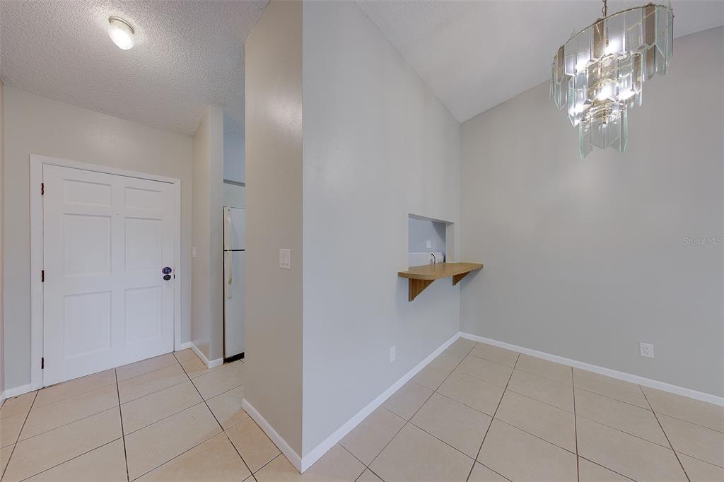 A dining area features a tile floor, a chandelier, and a pass-through window with shelving — 1109 E ROHE STREET UNIT A & B, TARPON SPRINGS, FL