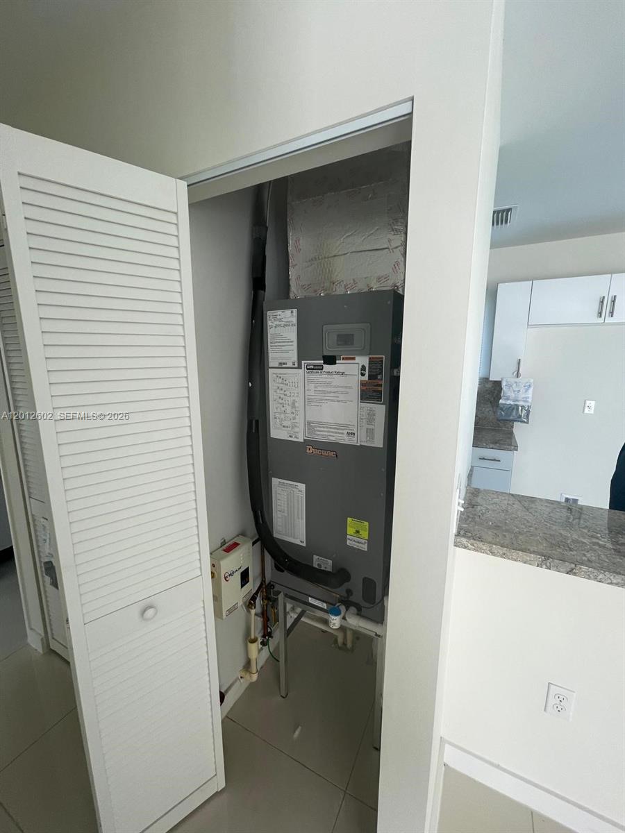 A utility closet contains a Ducane HVAC air handler unit next to a kitchen area — 2121 NW 72nd St # 2121, Miami FL 33147, MIAMI, FL